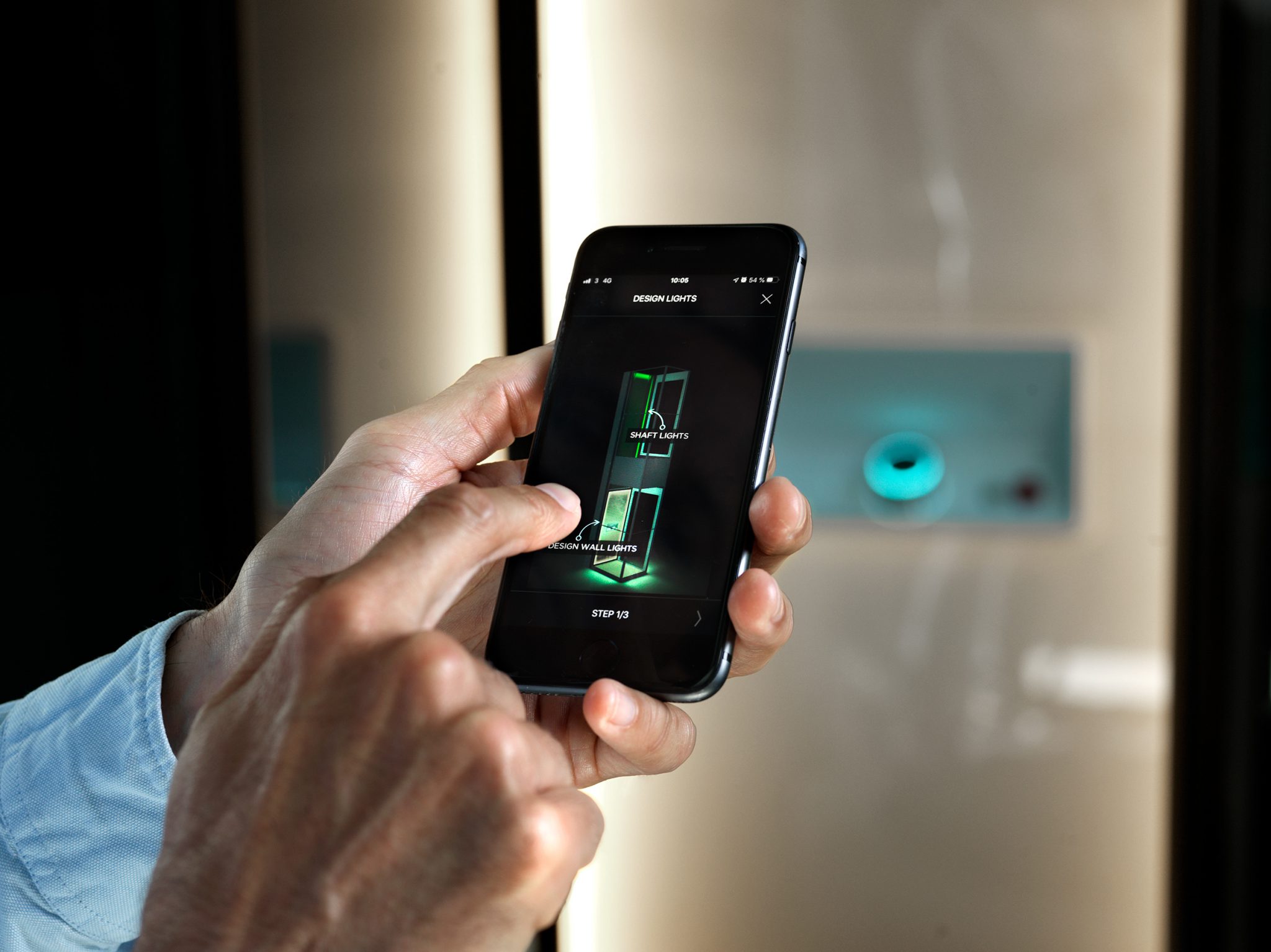 Picture of a hand with a smarthphone controlling the color of the lights inside the shaft and the designwall of the home lift Aritco HomeLift