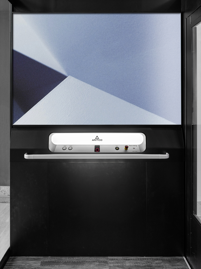 The home lift Aritco Homelift access with a designwall in blue colours