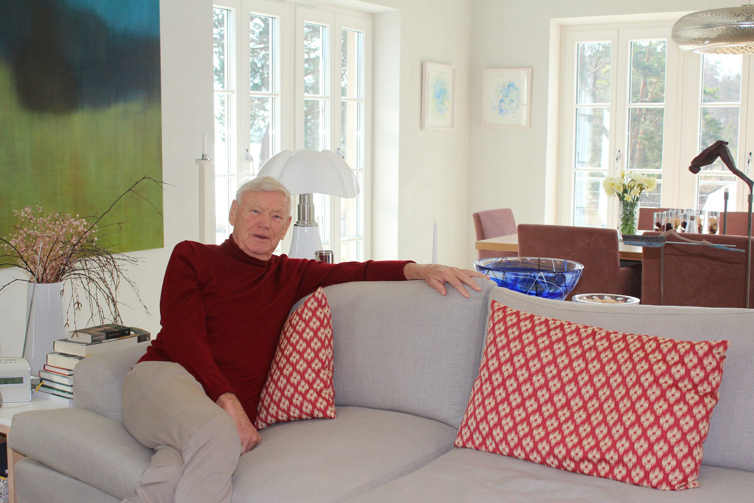 An older man sitting in a sofa in a scandinavian designed home with light colours