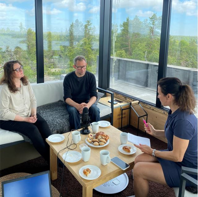 Two woman and a man sitting around a low table with Swedish fika