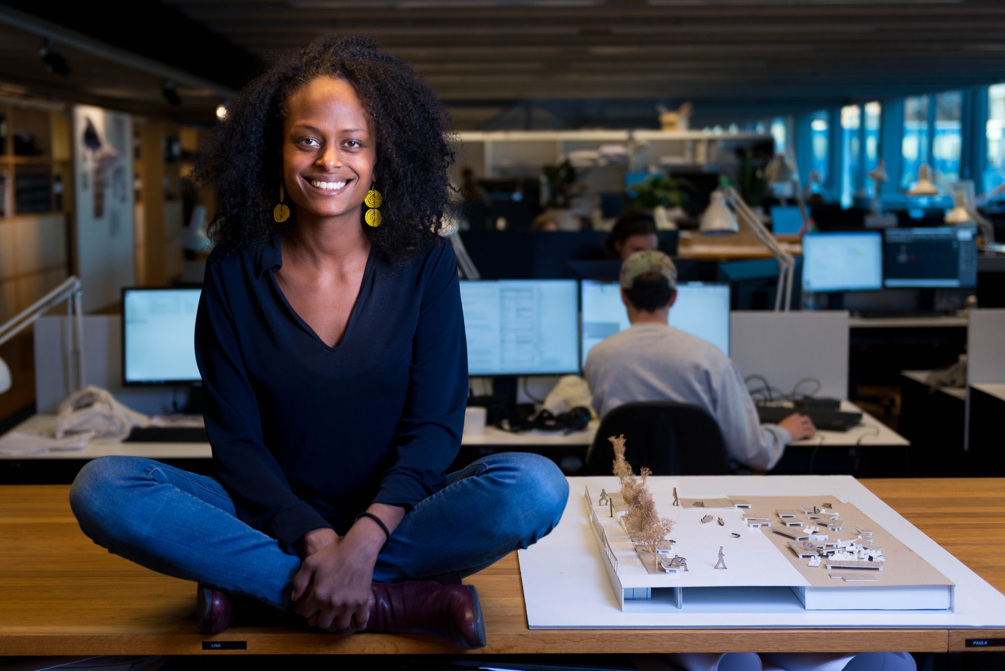 Viktoria Walldén, Anthropologist at White Arkitekter sits on a desk. Photo: Anders Bobert
