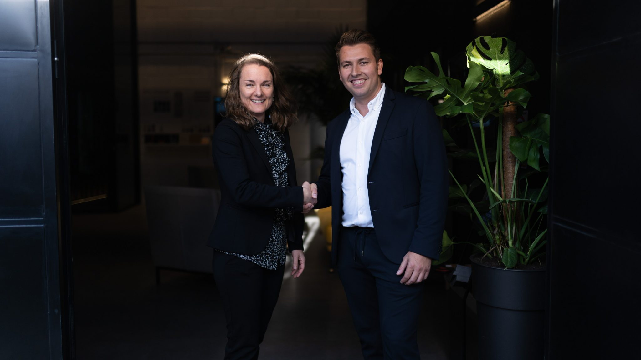 A woman and a man dressed in black shaking hands